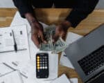 Picture of man at table with computer, phone and paperwork holding bills
