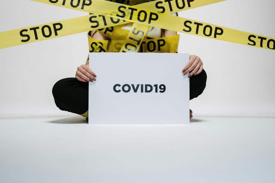 Person Holding Covid Sign With Yellow Caution Tape