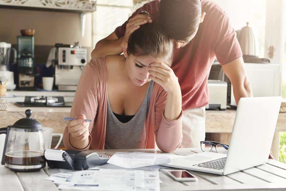 Couple at home stressed out looking at their computer and paperwork