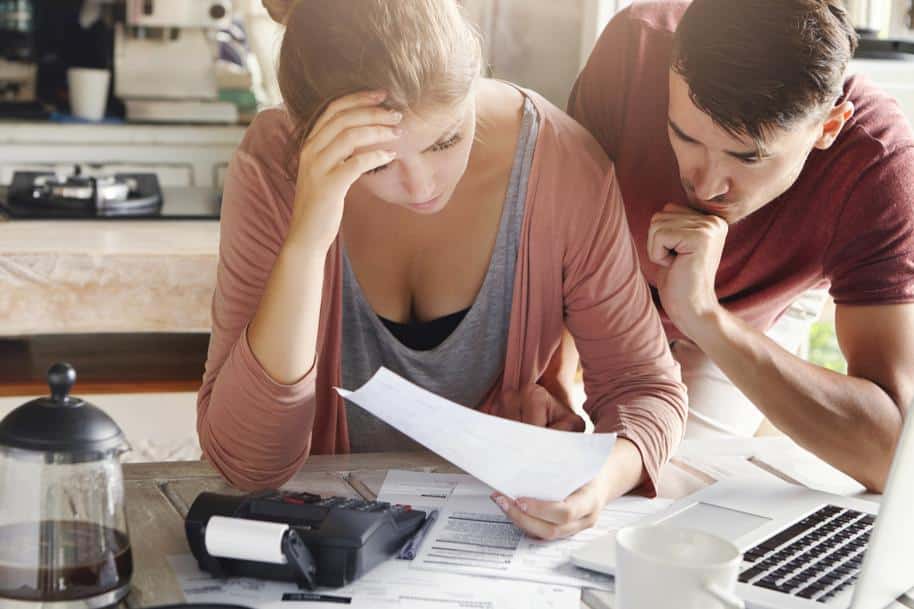 Couple looking frustrated while calculating taxes.