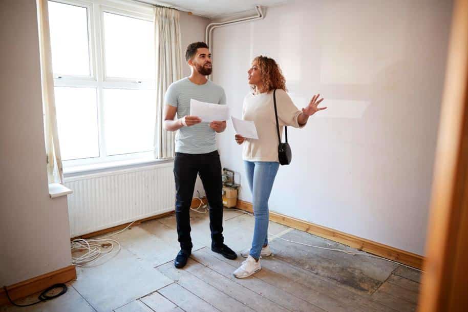 Couple holding papers talking in a property being renovated