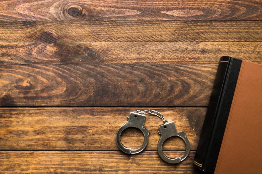 Handcuffs next to a leather-bound book on a wood desk