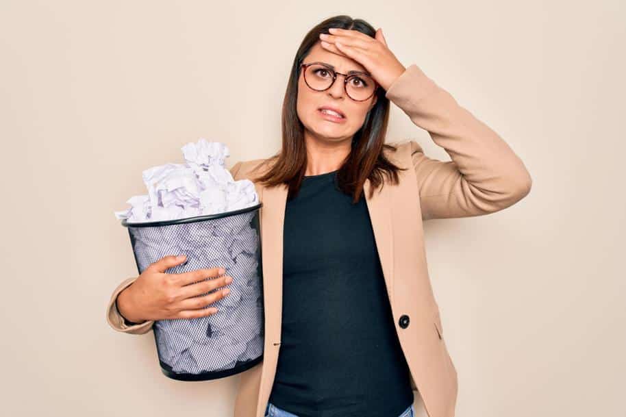 Young brunette business woman holding full paper bin of crumpled receipts